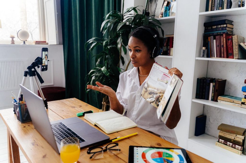 Mastering the First Impression: Your intriguing post title goes here Woman conducting online teaching session at home with laptop and books.